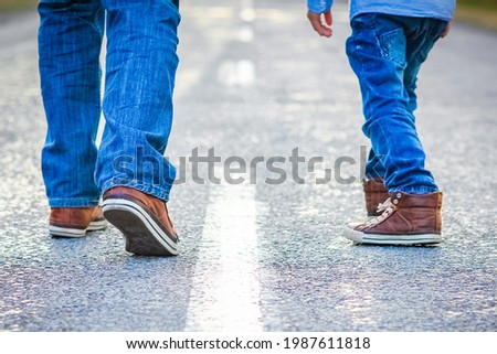 Beautiful feet of parent and child on the road in the park on nature travel