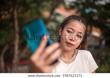 A young woman takes an angled selfie of herself. A rebellious look with a nose ring and a large bling necklace.
