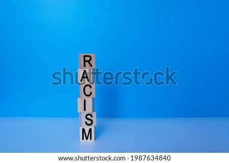 Racism text on wooden block with blue background