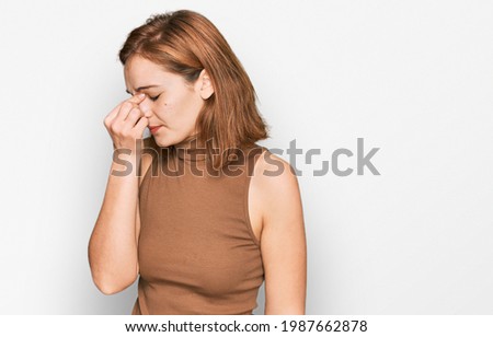 Young caucasian woman wearing casual clothes tired rubbing nose and eyes feeling fatigue and headache. stress and frustration concept. 