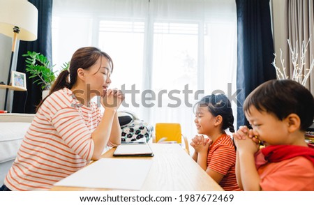 Family praying and worship to GOD with church online sunday service.Live Church with bible.Mother kid sibling praying on holy bible study at home.Lockdown worship.Christian faith hope.Online church. Royalty-Free Stock Photo #1987672469