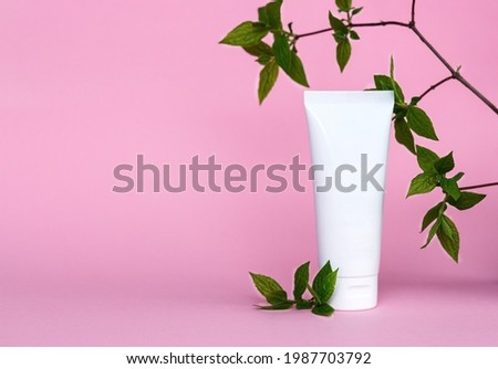 Cream tube on pink background. Cosmetic skincare product blank plastic package. White unbranded lotion, balsam, hand creme, toothpaste mockup