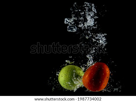 fresh red tomato and lemon splash falling into water on black background               