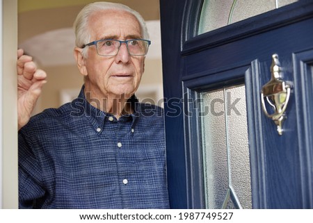 Anxious Senior Man At Home Looking Out Of Front Door Royalty-Free Stock Photo #1987749527