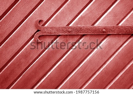 Old metal door hinge on wooden door in red tone. Abstract background and texture for design.