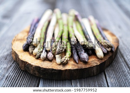 Green, purple and white asparagus sprouts on wooden board closeup. Top view flat lay. Food photography