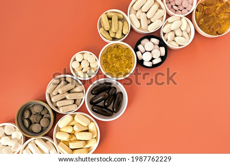 close-up of multivitamin biologically active supplements on coral background. mental wellbeing and personal health concept Royalty-Free Stock Photo #1987762229