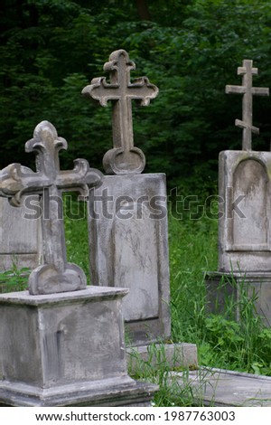 scenery for ancient graves and burials with tombstones and crosses made of weathered stone. View of a stone Cross with other crosses in the background