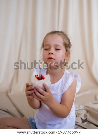 little birthday girl holds a cupcake with a candle and makes a wish on a beige background with a place for text