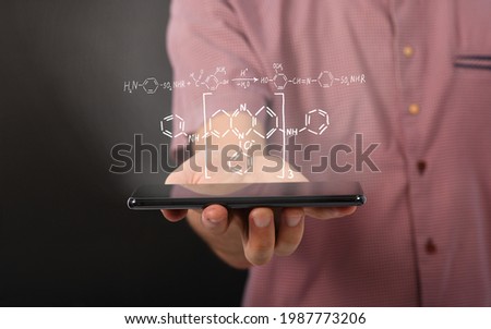 Man hand holding horizontal the black tablet computer with reaction diagram of organic chemical compounds. Isolated on black background. High resolution photo. 
