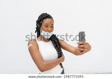 Afro american woman with a band aid taking a photo of herself: Selective focus. Health care and vaccination concept.