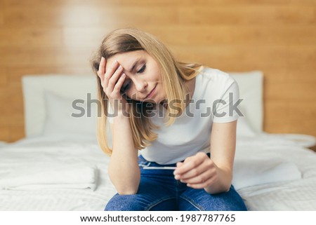 Title: Sad one woman complains about pregnancy test sitting on sofa in living room at home, frustrated with results

