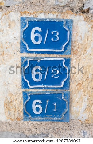 Enameled house number 6, door number six on a blue metal plate. Number is written with a serif font.