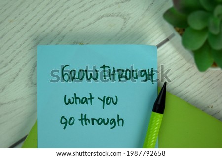 Grow Through What You Through write on sticky notes isolated on Wooden Table.