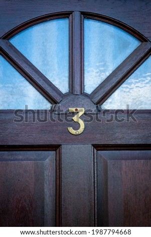 House door number 3 on a  dark wooden front door with glass