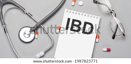 In the notebook is the text ibd, next to a stethoscope, pills and glasses.