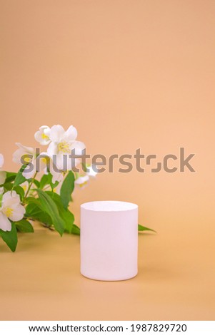 Round high podium to showcase cosmetics, products on a beige background and jasmine