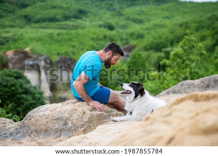 man with his dog sitting on a rock enjoying nature