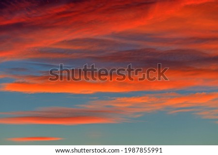 Image of orange glowing clouds in evening sky at sunset