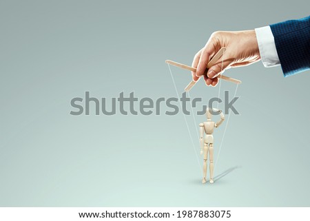 Male hand, puppeteer controls puppet, doll salutes, soldier. The concept of the army, orders, manipulation, control army Royalty-Free Stock Photo #1987883075