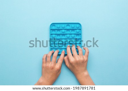 Hands of a child with an anti-stress toy on a blue background. A popular anti-stress product.