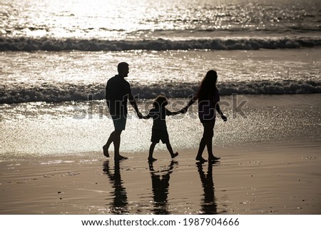 Silhouette of father, mother and child son holding hands and walking on beach. Sctive fanily lifestyle, parents with children on summer vacations.