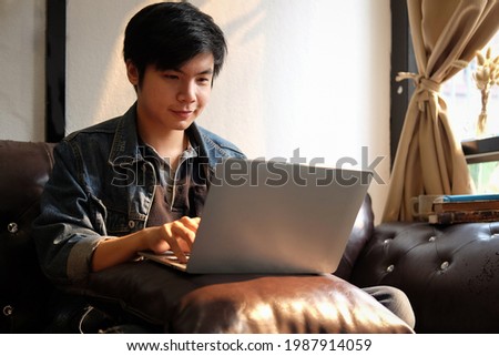 Man working from home on laptop computer while sitting at the living room, drinking coffee	