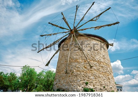 Ancient windmill in Golyazi (uluabat) bursa and it main structure made of stone and with wooden propeller with magnificent blue sky and green trees background during spring time