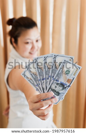The right hand of a white woman showing a mock-up hundred dollar banknote for shopping. selective focus.