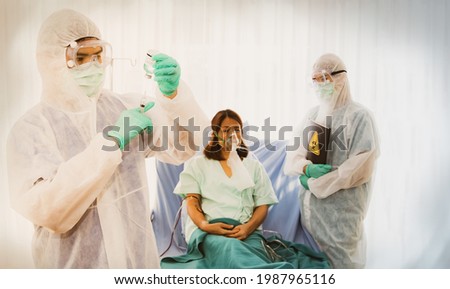 Doctors and medical team wearing PPE uniforms prepare to inject Coronavirus (Covid-19) vaccine to infected female patients to build immunity and monitor symptoms carefully.
