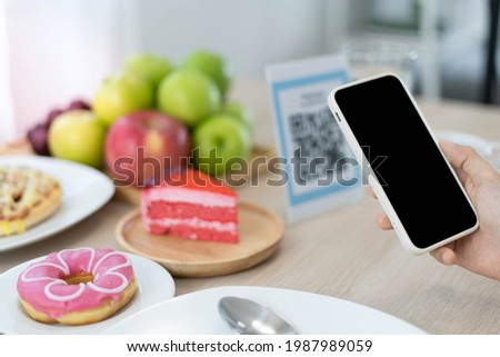 Women use phone to scan qr code to select food menu and collect points. Scan to get discounts or pay for food. The concept of using a phone to transfer money or paying money online without cash.