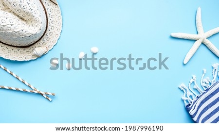 A sun hat, a starfish and white small seashells on a blue background. Flat lay, summer, backgrounds. 