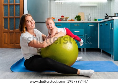 Yoga at home. A young mother leaning on a fit ball and posing with your baby. The concept of fitness with children at home.