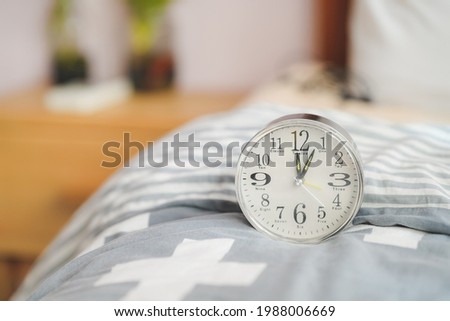 A round alarm clock sits on the blanket next to the bed. bedroom design.