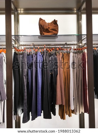 many rows with hangers with different colorful pants at clothing store 

