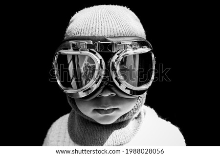 Portrait of an Asian boy pilot in vintage aviator helmet and goggles. Black and white vintage photograph.