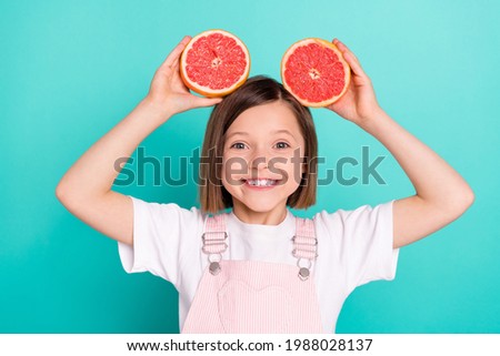 Photo of charming sweet school girl wear pink overall smiling holding head fruit slices isolated teal color background Royalty-Free Stock Photo #1988028137