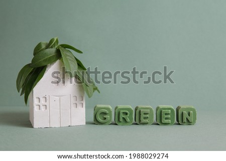 Green House nature Ecology Architecture on green background. Mini house made of concrete, green leaves of tree