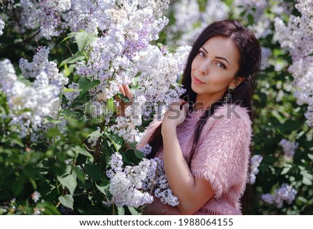 a beautiful young woman walking in a spring garden and Enjoying the Smell of Lilac. Aromatherapy and Spring Concept