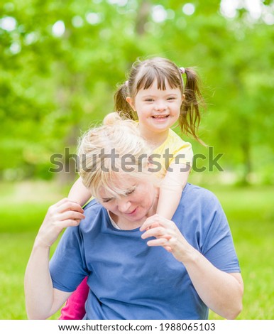 Mother and happy little girl with special needs have a fun in summer park