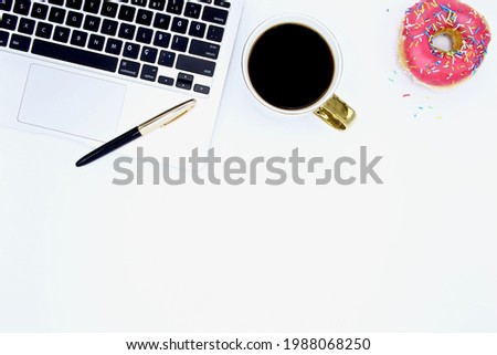 Flat lay of top view office desk white table with laptop, pink donut, coffee and gold black pen copy space
