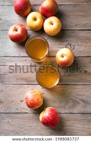 Apple cider or juice drink and apples on wooden background, top view, copy space. Garden organic red and yellow apples and fermented drink.