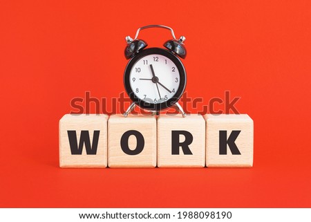 Alarm clock and wood blocks with text WORK on bright red background. Business, career, waste of time, procrastination concept.