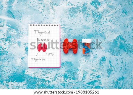 Notebook with drawing of thyroid gland and pills on color background