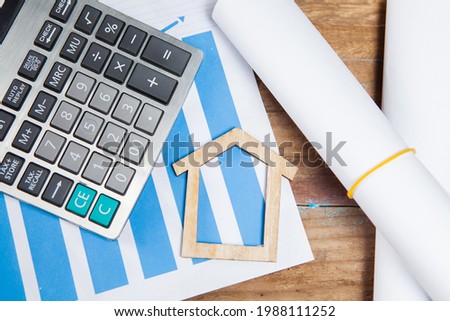 calculator, statistics and house on a wooden table