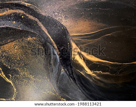 Abstract black art with gold — black background with beautiful smudges, stains and splashes made with alcohol ink. Gold fluid texture resembles space, night sky, stone, smoke, watercolor or aquarelle. Royalty-Free Stock Photo #1988113421