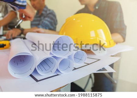 Plans and documents are placed on desks in the engineering team's office to prepare for the meeting of the designers, engineers and foreman teams to supervise the construction work as planned. Royalty-Free Stock Photo #1988115875