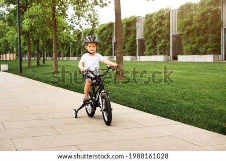 Boy in protective helmet rides  bicycle and smiles, in park. Active rest. Children's sports. 
