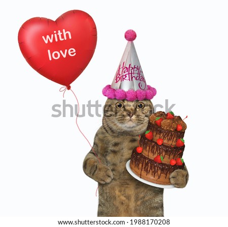 A beige cat in a party hat holds a holiday chocolate truffle cake and a red heart shaped balloon. White background. Isolated.