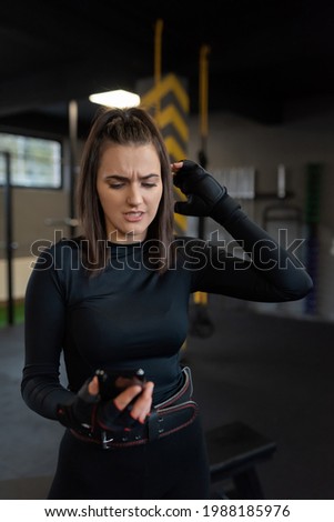 A confused woman beginner in fitness uses a smartphone to find exercises to do in training. High quality photo
